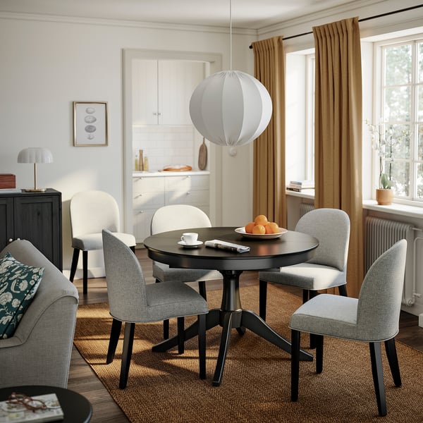 Modern dining room with ROSENTORP chair in beige-grey. Soft, sleek design around small table with lamp.