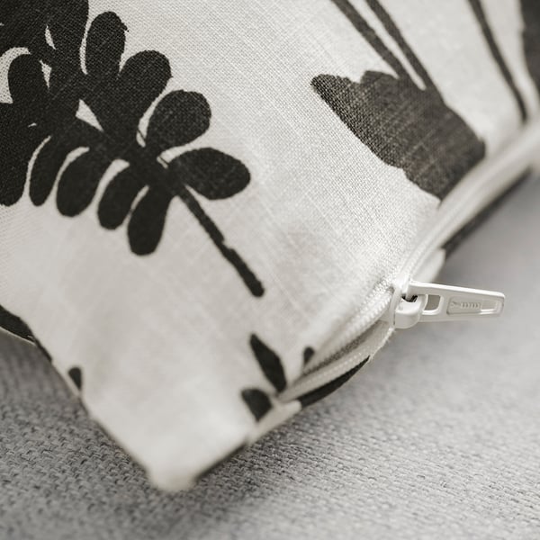 Close-up of zippered cushion cover featuring black floral designs on white fabric.