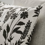 Black floral pillow on white fabric, showcasing elegant craftsmanship.