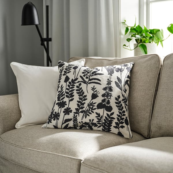 Beige couch with herbarium-inspired throw pillow and floor lamp.