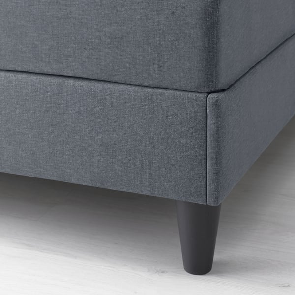 Close-up of grey upholstered bed leg, showing sturdy wood finish and padded support.