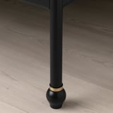 Elegant black bed leg with gold accent on hardwood floor.