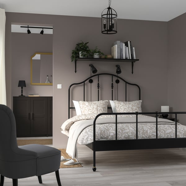 Cozy bedroom with SAGSTUA bed, floral bedspread, plants, and lantern.