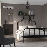 Cozy bedroom with SAGSTUA bed, floral bedspread, plants, and lantern.