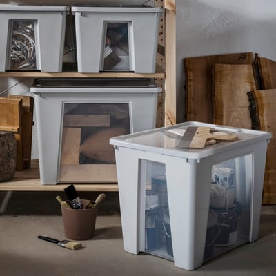 Grey SAMLA boxes with clear windows, shelves stocked with paint supplies and wooden planks.