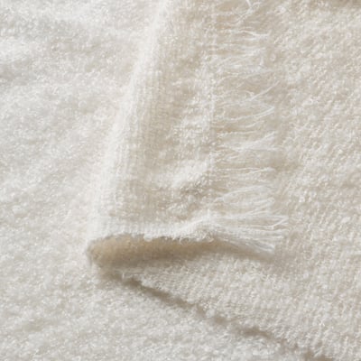 White SANDBRODD blanket, soft, textured, folded, fringed.