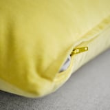 Close-up of soft, yellow cushion cover with smooth zipper, showcasing quality cotton velvet fabric.