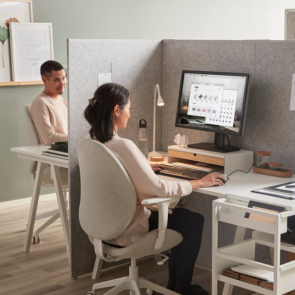 Office with gray room dividers and desks, each with computers and personal items.