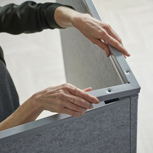 Person installs SIDORNA corner divider, securing panel with metal fitting.