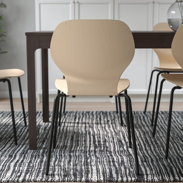 Chairs arranged around a table on a patterned rug. The design offers lumbar support and flexible backrests for comfort.