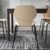 Chairs arranged around a table on a patterned rug. The design offers lumbar support and flexible backrests for comfort.