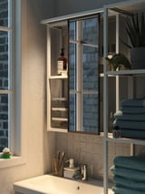 Modern bathroom with sink, storage, mirror, plants, and lighting.