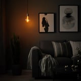 Cozy living room with SKAFTET lamp above gray sofa, abstract art, and cactus.