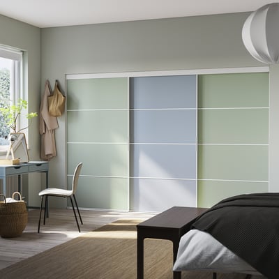 Modern bedroom with large SKYTTA wardrobe, frosted green sliding doors, wooden floor, and minimalist furniture.