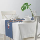 Blue embroidered table runner on white-covered table, surrounded by white chairs and clear glasses.