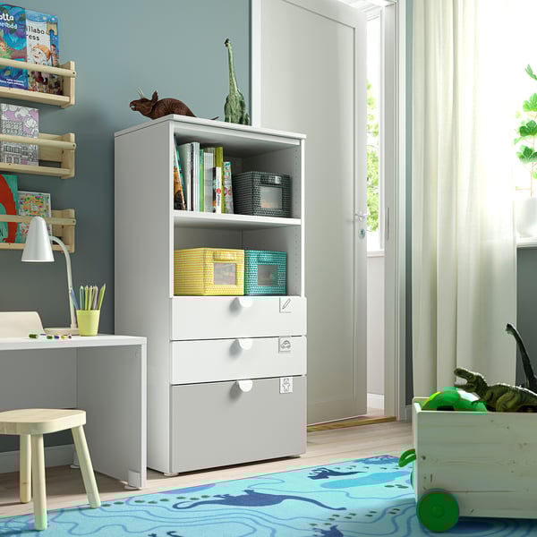 Childs room with white bookcase, desk, blue rug, dinosaur toys.