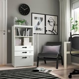 Modern home office with white SMÅSTAD bookcase, black chair, large wall clock, and abstract art.