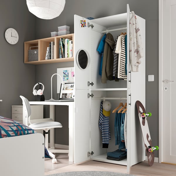 Small bedroom with white SMÅSTAD wardrobe, desk, chair, and skateboard. Wardrobe holds clothes and books. Desk has a computer and headphones.