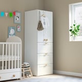 Baby room with white SMÅSTAD wardrobe, crib, and decor. Wardrobe has drawers, hooks, and closet space. Decor frames and banners.