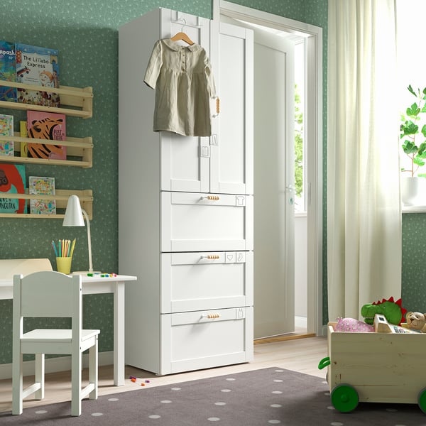 Childrens room with SMÅSTAD white wardrobe, shelves, desk, toys, and green accents.