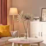 Modern living room with cream sofa, yellow pillow, coffee table, vases, bookshelf, lamp, red curtains.