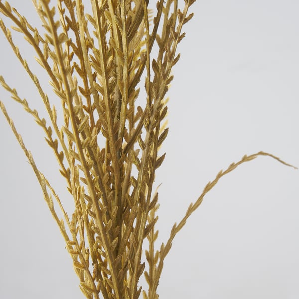 Close-up of artificial plant stem with fine, golden leaves. Lifelike texture and detail, perfectly mimicking natural foliage.