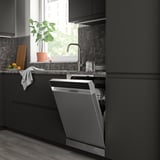 Modern dark kitchen featuring an open SÖDERBODA dishwasher, smaller than surrounding cabinets, near a window with a plant.