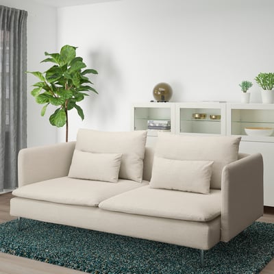 Modern living room: beige sectional sofa, green plant, shaggy rug, gold decor.