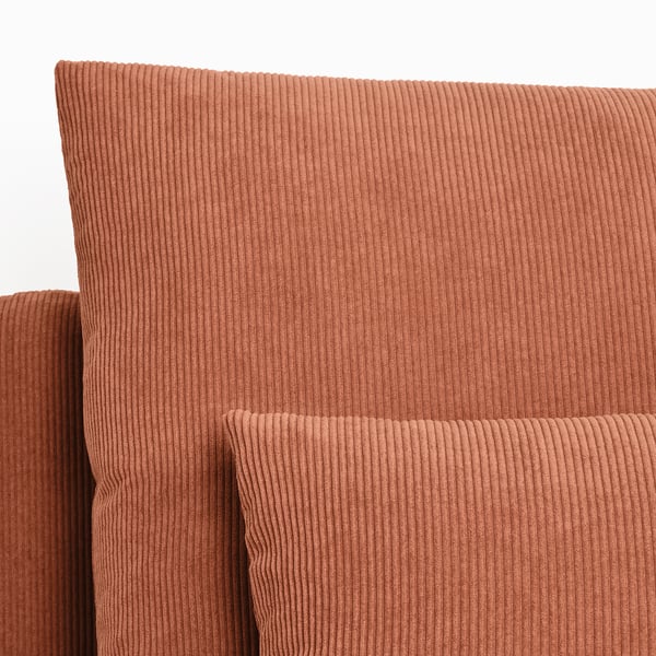 Close-up of a plush, textured terracotta-colored corduroy sofa, showcasing its soft, ridged fabric quality.