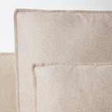 A plush, beige fabric sofa with a relaxed, deep-seated design, featuring clean lines and high legs for an airy look.