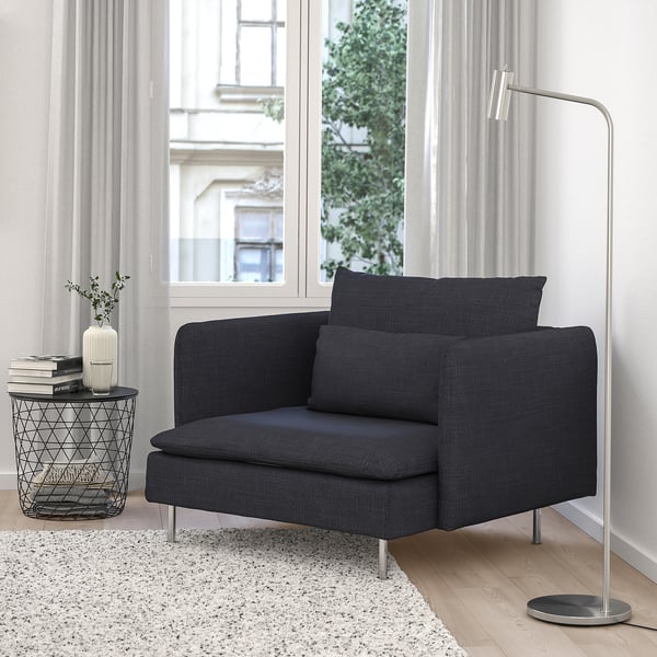 SÖDERHAMN chair in dark grey fabric by window with books, vase, and lamp.
