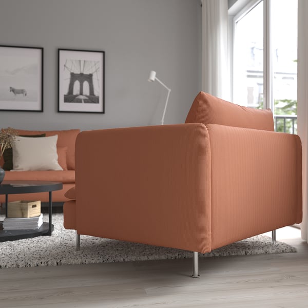 A modern living room an orange SÖDERHAMN sofa with deep seating and high legs. The sofas stylish, low profile provides comfort and relaxation.