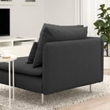 Dark gray modern sofa with three cushions, positioned in a cozy room with a white side table holding a coffee cup.