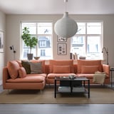 Modern living room with orange SÖDERHAMN sectional sofa, plush cushions, coffee table, pendant lamp, and window greenery.