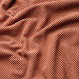 Rust-colored, textured fabric with wavy patterns; soft and plush, likely cozy and comfortable.