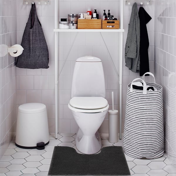 Bathroom with toilet, dark grey mat, white bin, striped basket.