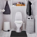 Bathroom with toilet, dark grey mat, white bin, striped basket.