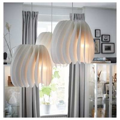 Three white modern pendant lamps hang near a large window, emitting a warm light. The lamps have a segmented, spherical design.