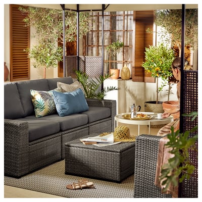 Modern outdoor living area with grey SOLLERÖN modular sofa, colorful pillows, round table, and potted plants.
