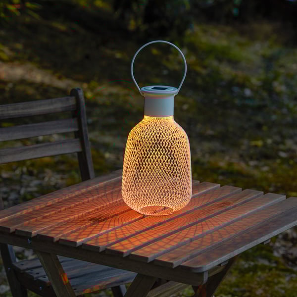 Solar lantern on wooden table, illuminating outdoors.