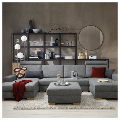 Grey u-shaped SÖRVALLEN sofa with red accents, against a concrete wall with mirror and shelves.