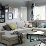 Modern gray l-shaped sofa with colorful pillows, a cozy blanket, and a sleek coffee table in a stylish living room.