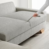 Hand pulling out sofa bed extension on light grey SÖRVALLEN sofa.