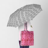 Person with SÖTRÖNN umbrella and red recycled polyester shoulder bag.