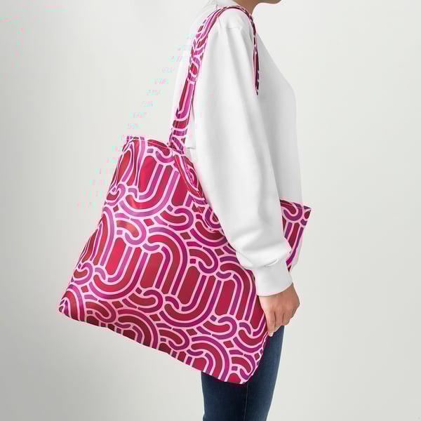 Person carrying a red patterned reusable tote bag over shoulder.