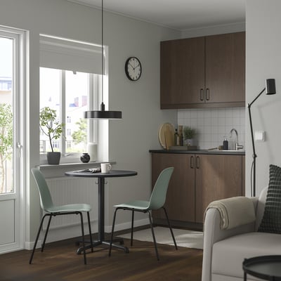 Modern kitchen with light green STENSELE stackable chairs, minimalist design, wood floor, and black accessories.