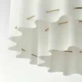 Elegant pendant lamp with wavy textile shade and gold accents, exuding a soft, inviting light.