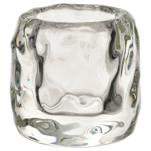 STOCKHOLM 2025 ice cube-shaped tealight holder, clear glass, thick design, elegant, emits warm glow.