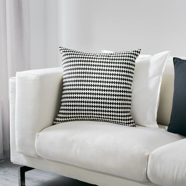 Large white couch with black/white checkered pillow, stylish & cozy.
