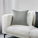 Large white couch with black/white checkered pillow, stylish & cozy.